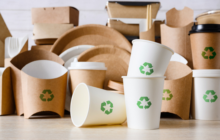 Event-Recyclable Paper Packaging Assorted paper packaging goods, such as plates, cups, and containers, with green recycling symbols